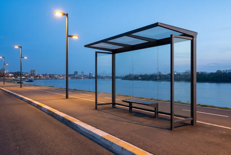 Empty bus shelter by a riverside road at dusk